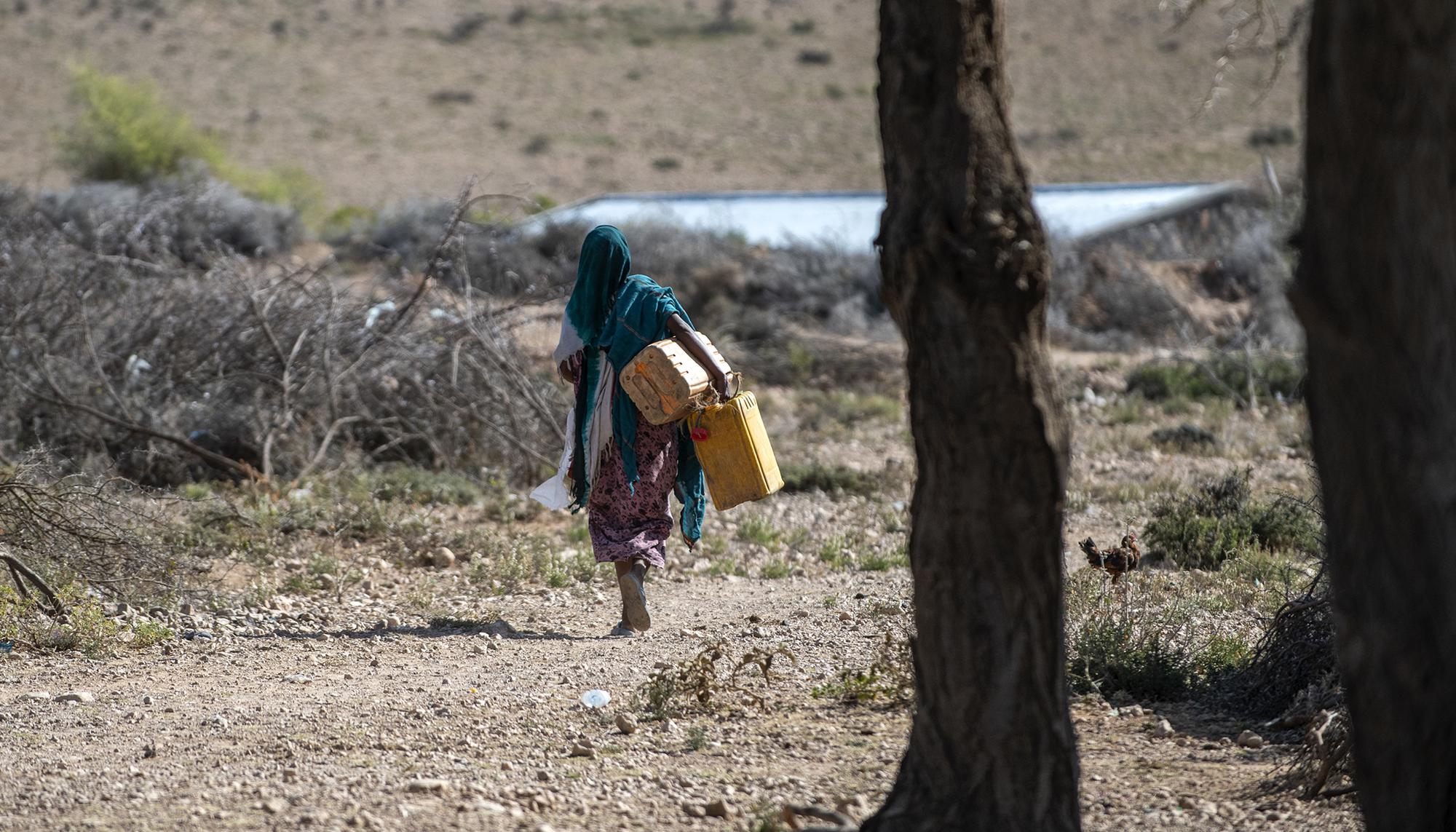 Mujer cargando con bidones de agua
